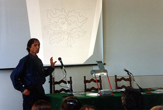 A speaker presents a projected drawing to participants in the lecture room.