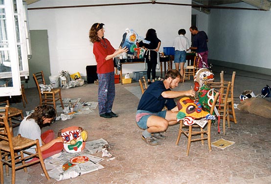 Participants paint and assemble colourful masks in the workshop hall.