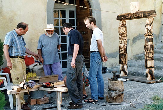 Participants gather around a collaborative wood-carving project in the courtyard.