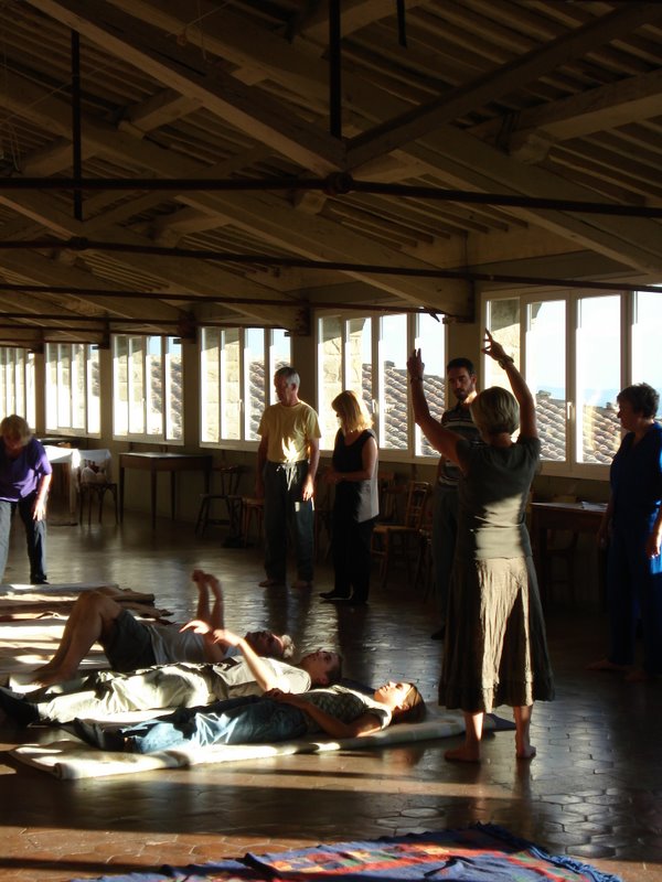 Participants explore movement and theatre in a sunlit workshop hall.