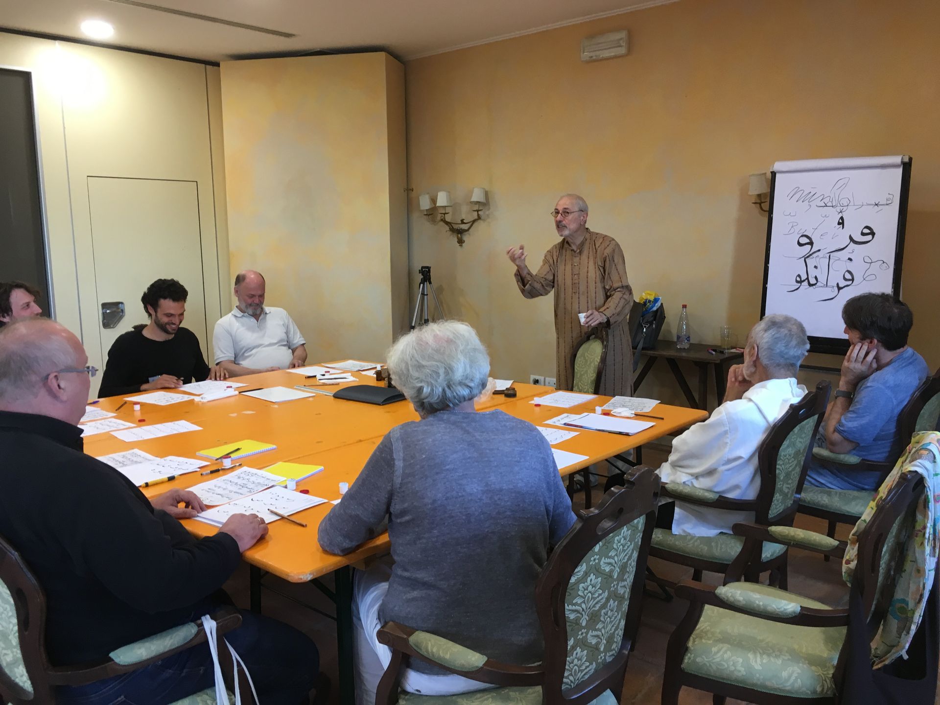 Participants practise calligraphy at a long table during a workshop in Todi.